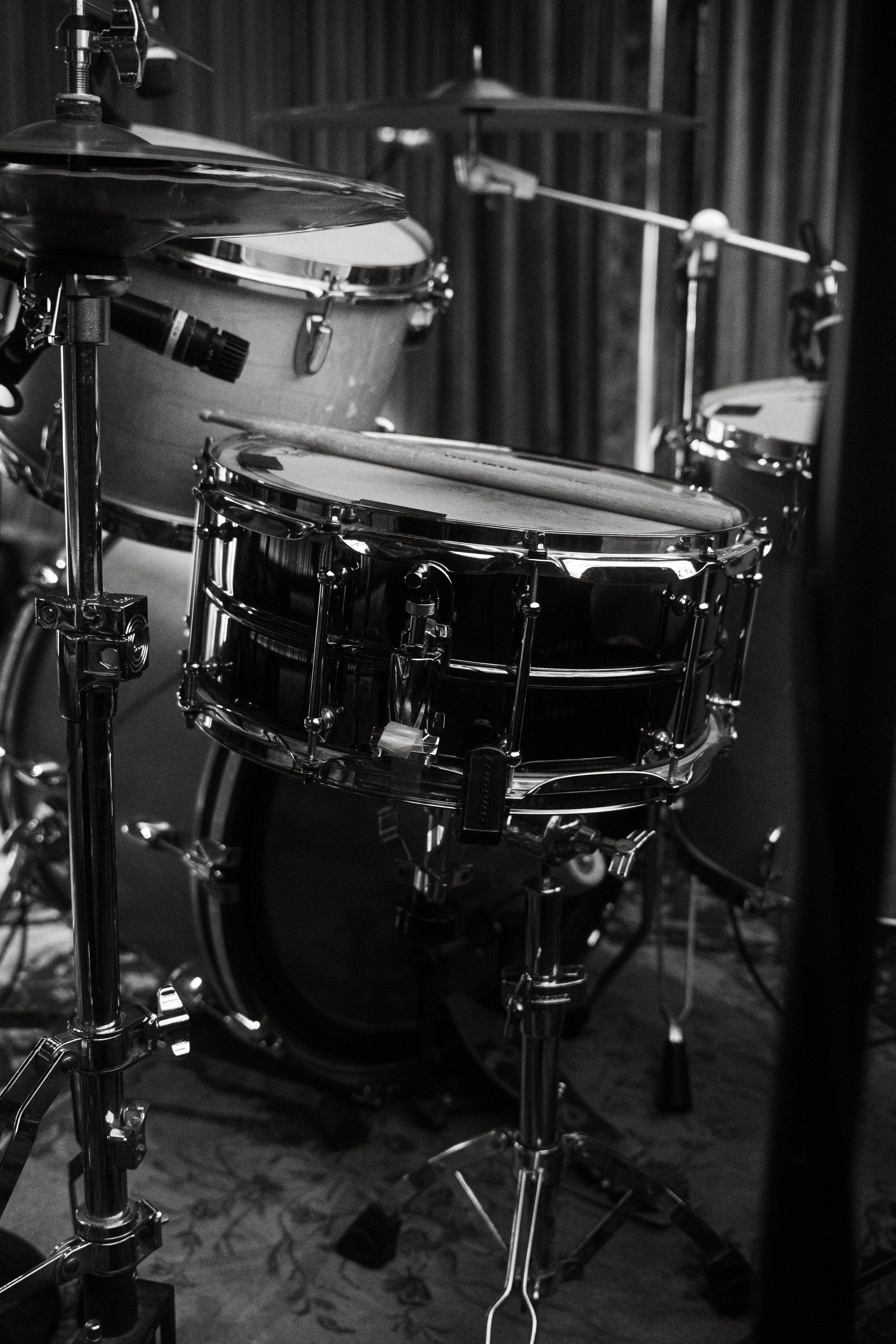 Monochrome close-up of a drum kit in a studio setting, highlighting the snare drum.