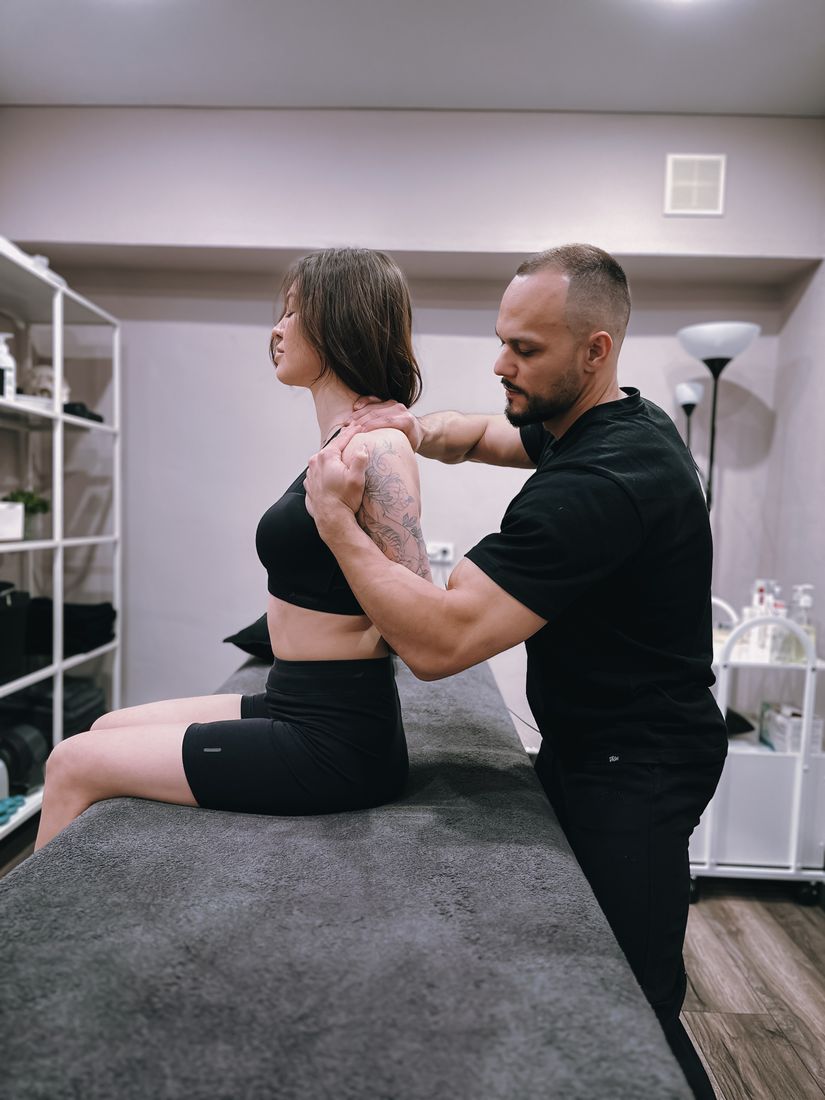 Chiropractor gently adjusting a patient's shoulder in a bright, modern clinic