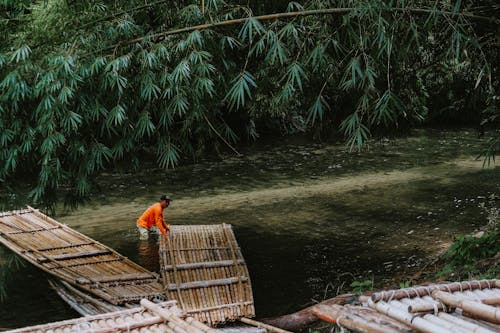 Человек в реке Тянет бамбуковый плот к воде