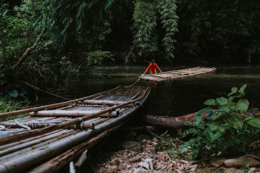一个人在风景优美的雨林河流中漂流，四周竹林环绕