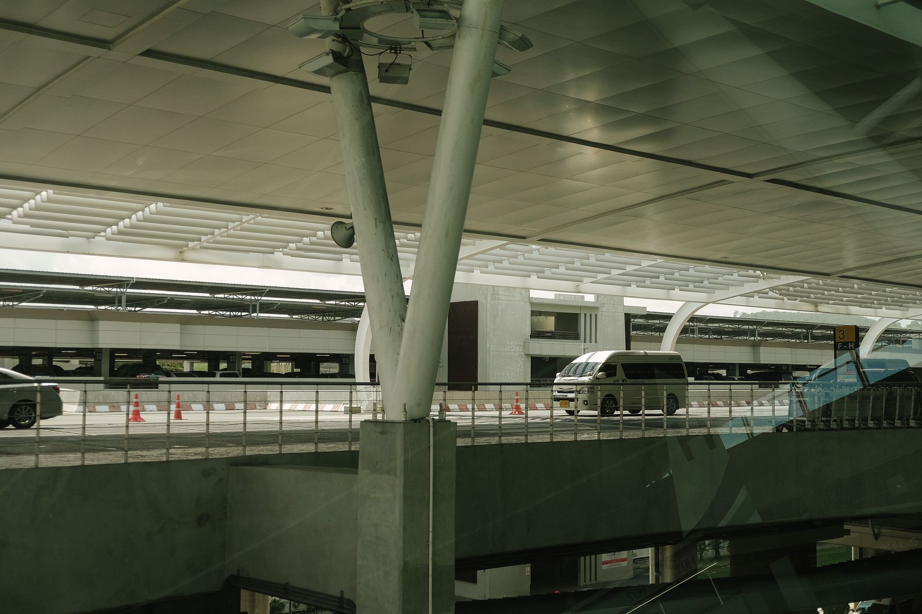 A modern airport departure terminal with vehicles outside during the day