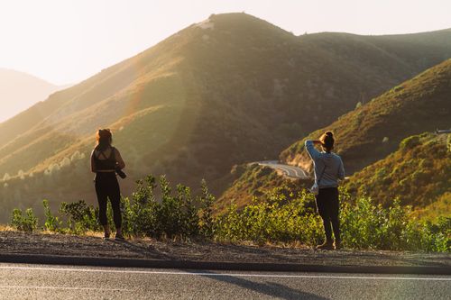 Free Two hikers enjoying a scenic view of mountain roads at dusk. Stock Photo