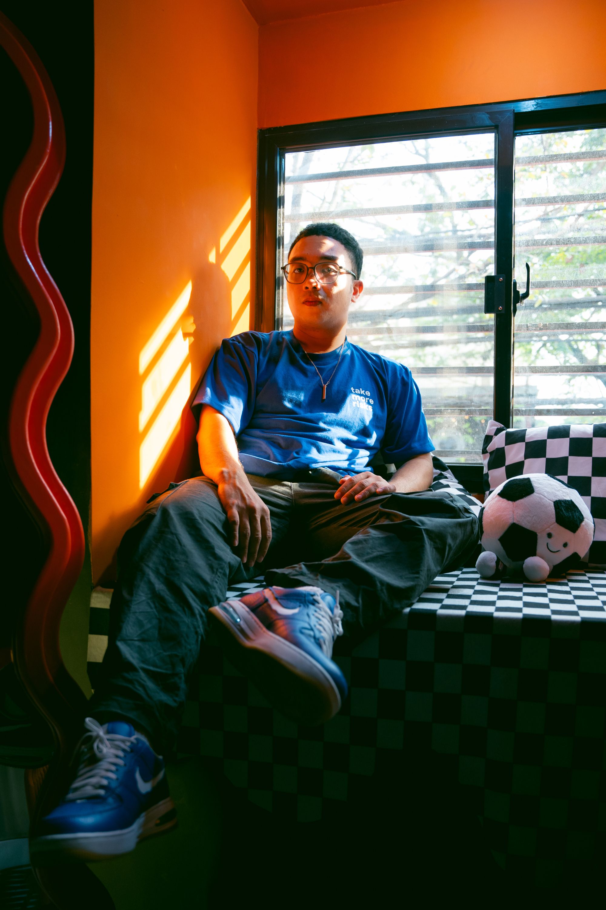 Young man sitting by window with bright sunlight in relaxed home setting.