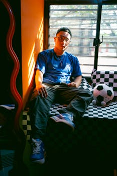 Young man relaxing by the window with stylish decor and natural light.