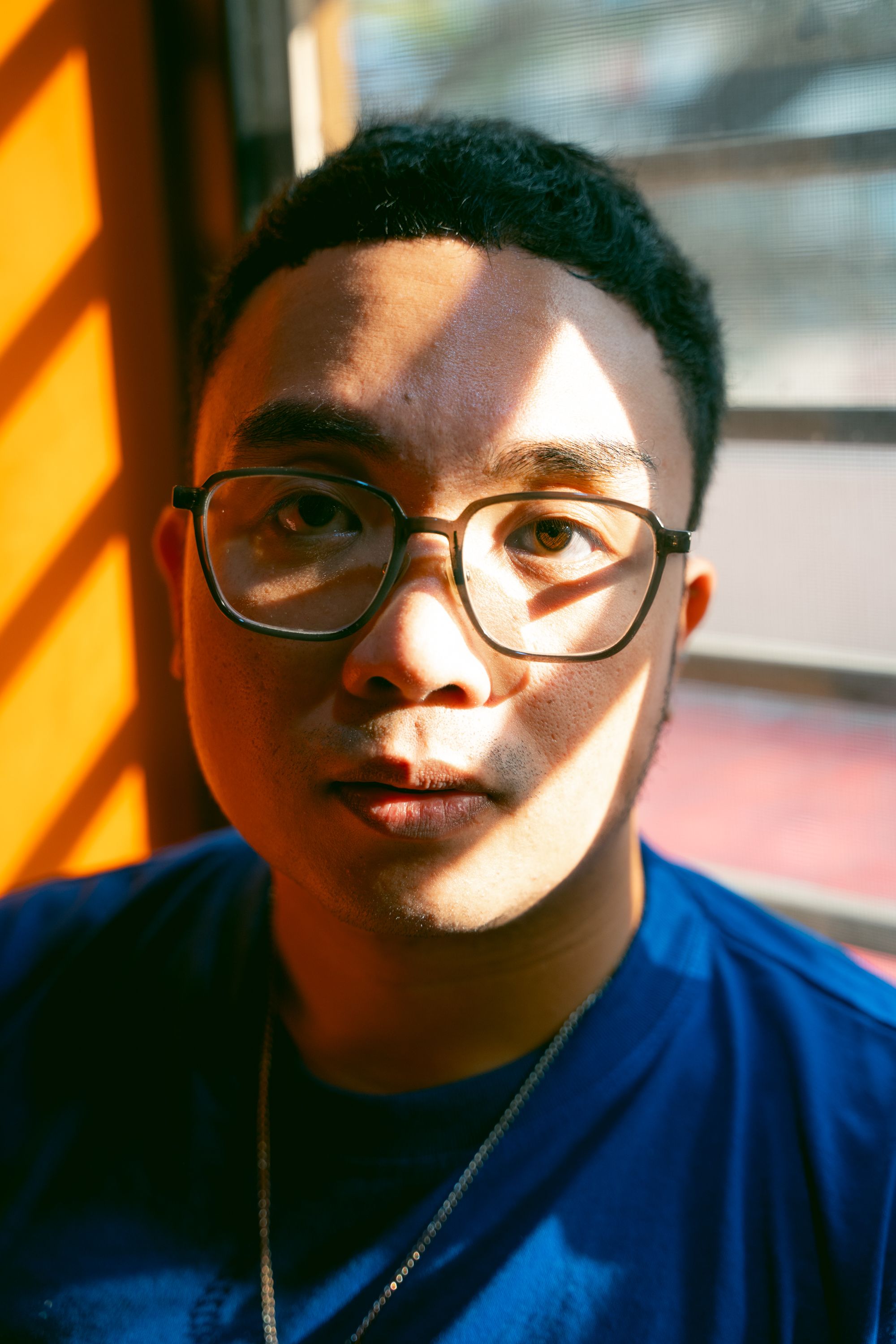 Close-up portrait of a man in sunlight wearing glasses, feeling pensive.