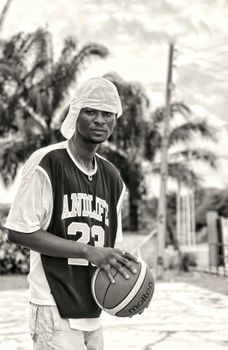 A young man holding a basketball outdoors in Moro, Nigeria.