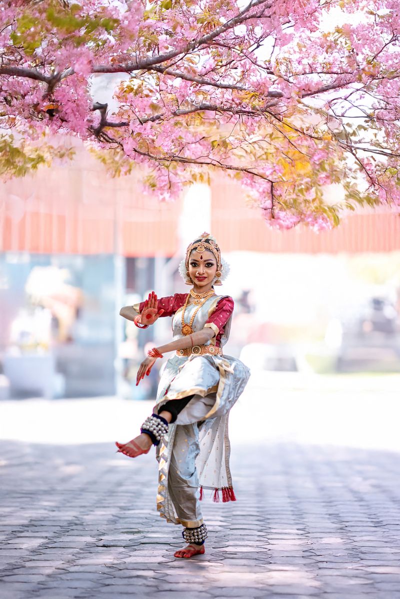 Traditional Indian dancer performs under cherry blossoms in Kerala
