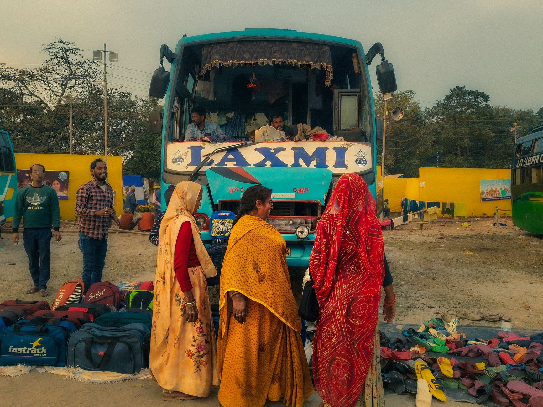 A vibrant scene at an Indian bus station with passengers and luggage awaiting departure.