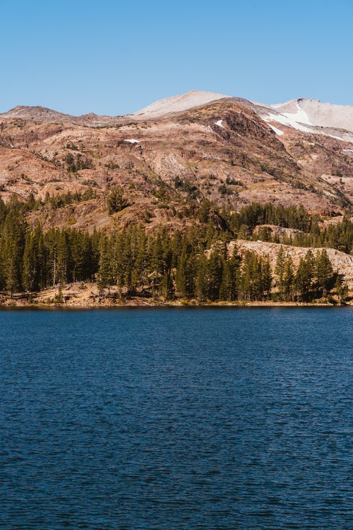 Free Serene mountain lake surrounded by coniferous forest and rocky peaks, perfect for nature lovers. Stock Photo