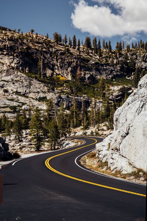 Free Winding road through a rocky mountain landscape under a clear sky, ideal for travel and nature themes. Stock Photo