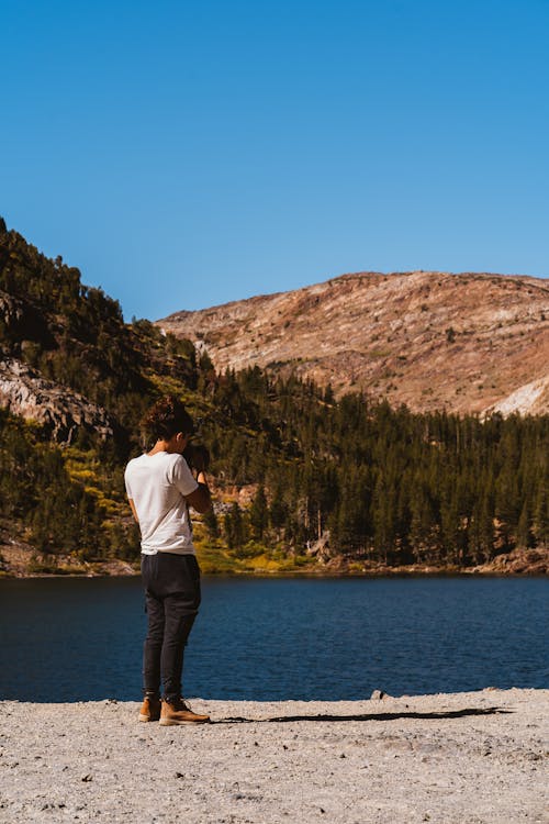 Person Talking A Photo Of The Lake Surrounded By idyllic scenery 