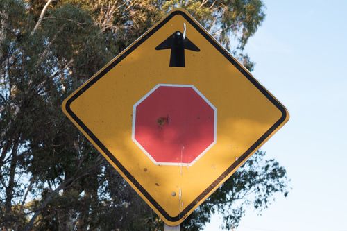 Free Yellow traffic sign with an arrow and faded red octagon symbol outdoors. Stock Photo