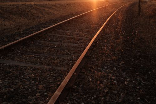 Free Warm sunset illuminating a rural railroad scene with vibrant light and nature. Stock Photo