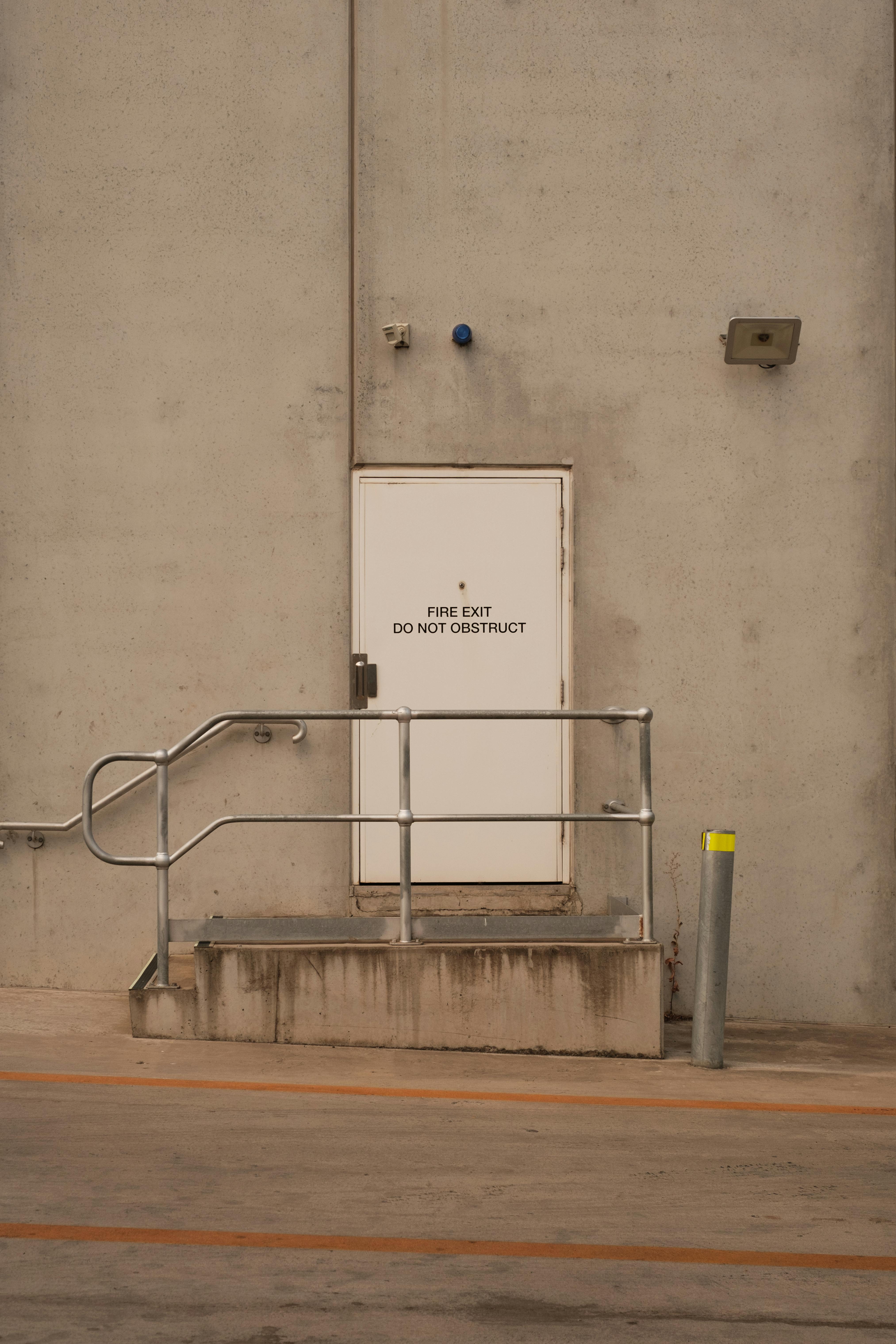 Gratis Industriel brandudgangsdør med metalgelænder på en betonvæg. Lagerfoto