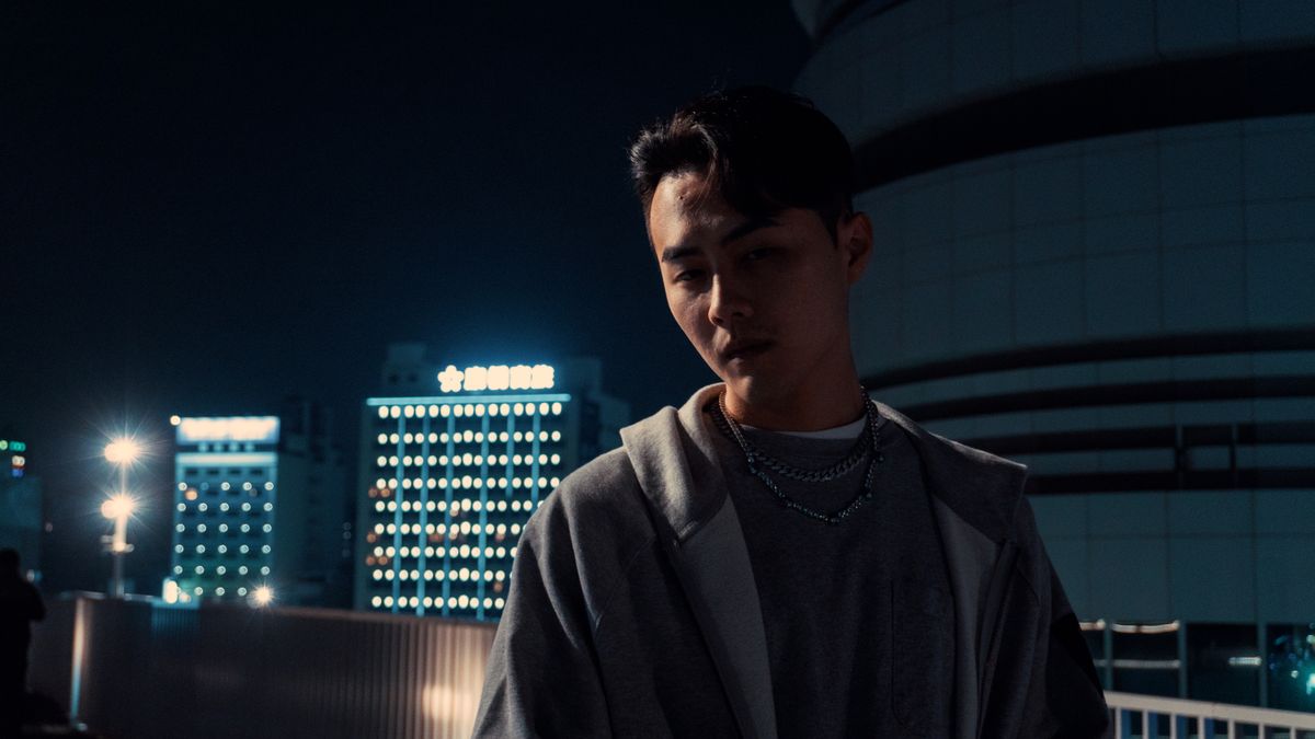 Man lit by warm storefront glow on a dark night street