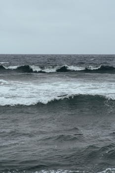 在阴沉的天空下，汹涌的海浪相互撞击，展现出大自然运动的壮美