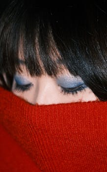 Artistic portrait highlighting blue eye makeup and red sweater contrast.