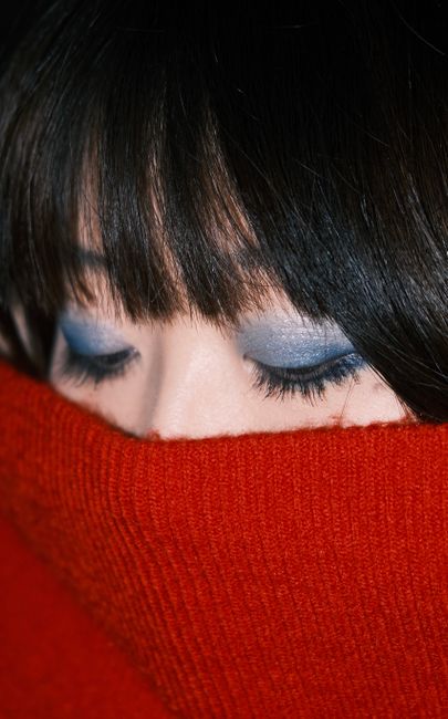 Artistic portrait highlighting blue eye makeup and red sweater contrast.