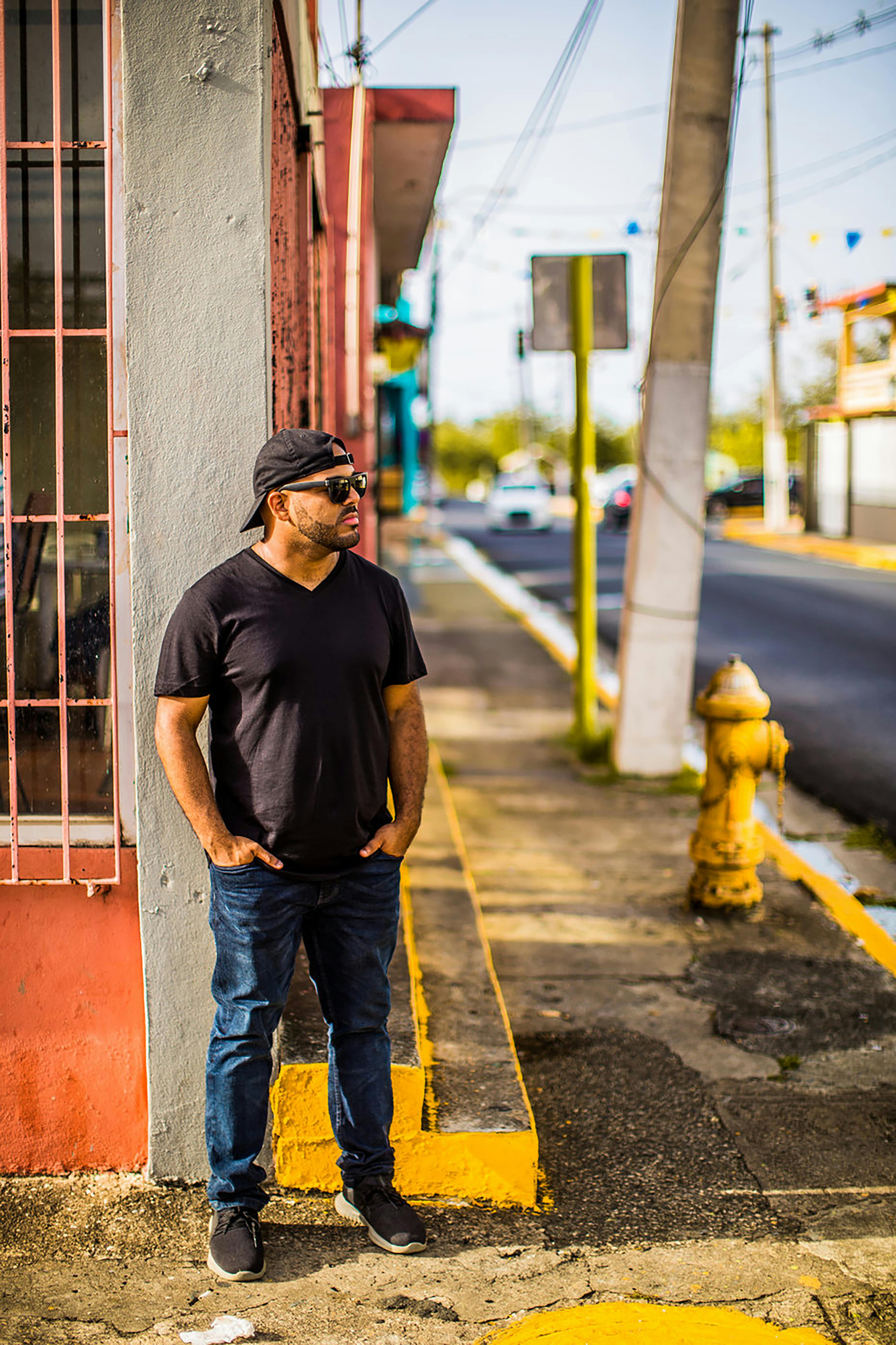 一名男子在日光下，以休闲风格站在充满活力的城市街道上