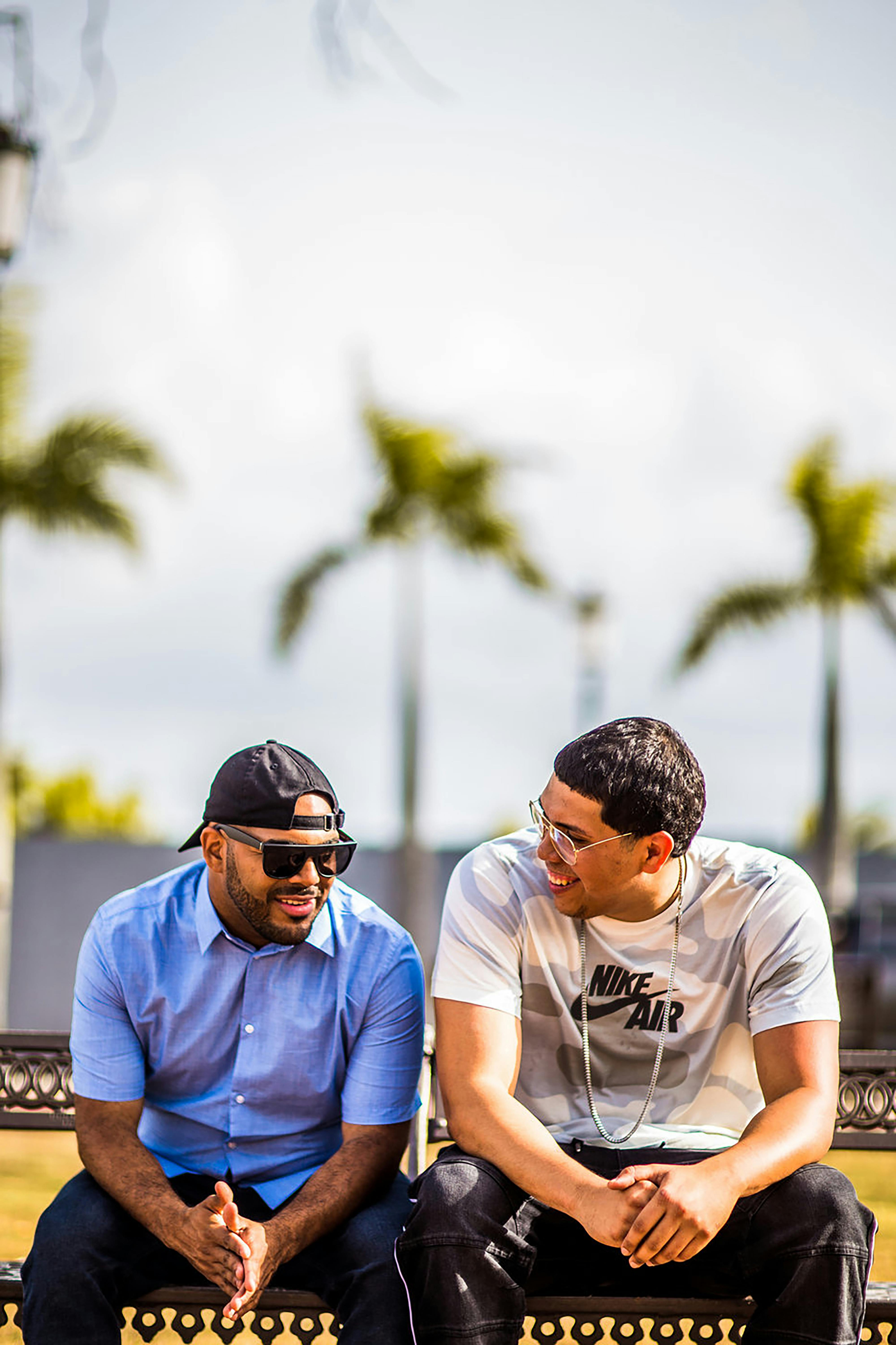 Two Men In Casual Wear Sitting Together On A Bench Talking And