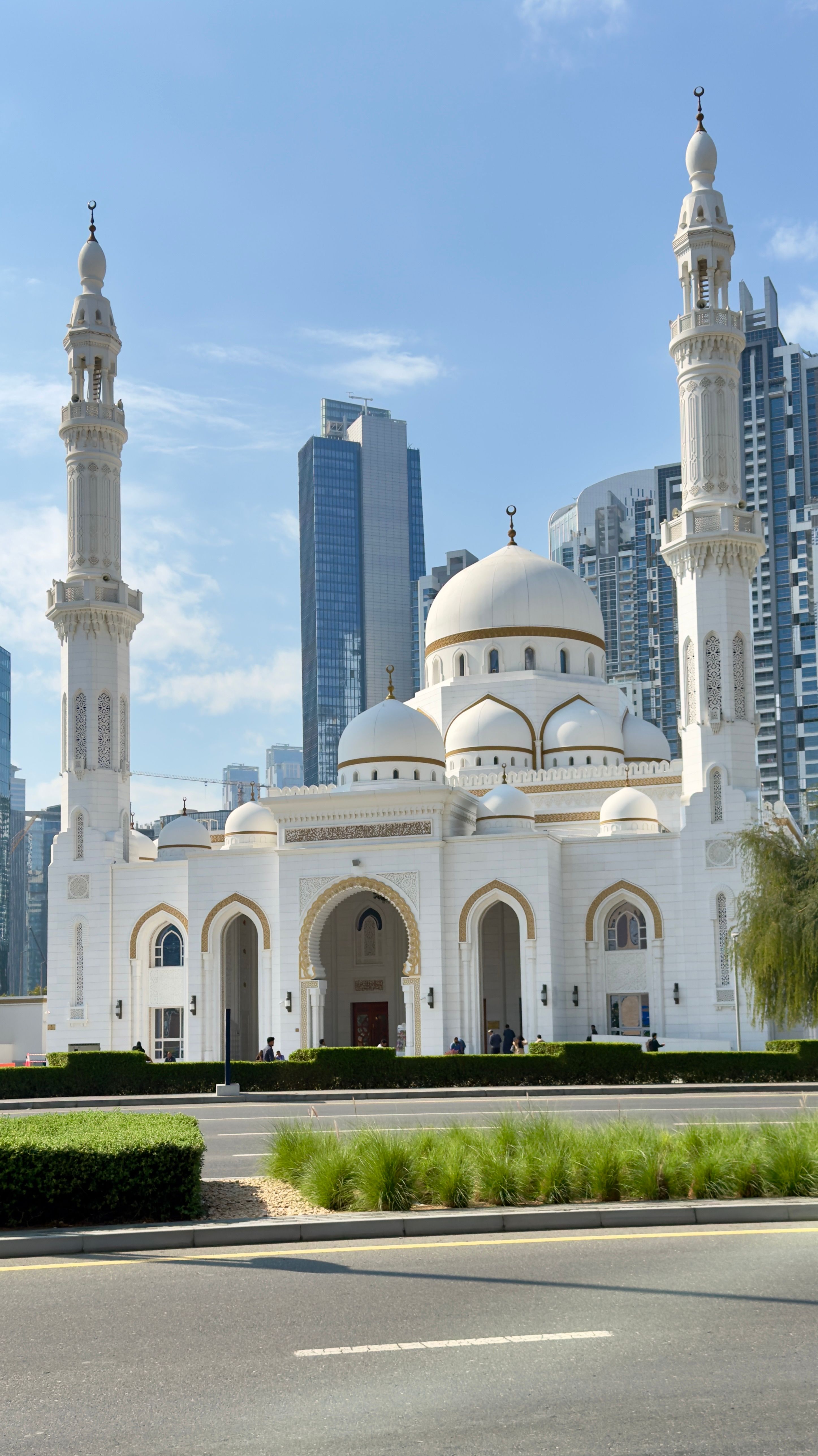 Stunning white mosque with prominent domes and minarets set against Dubai's modern skyline, UAE.