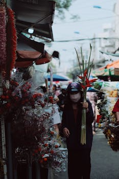 A vibrant flower vendor in a bustling street market, holding tropical blooms.