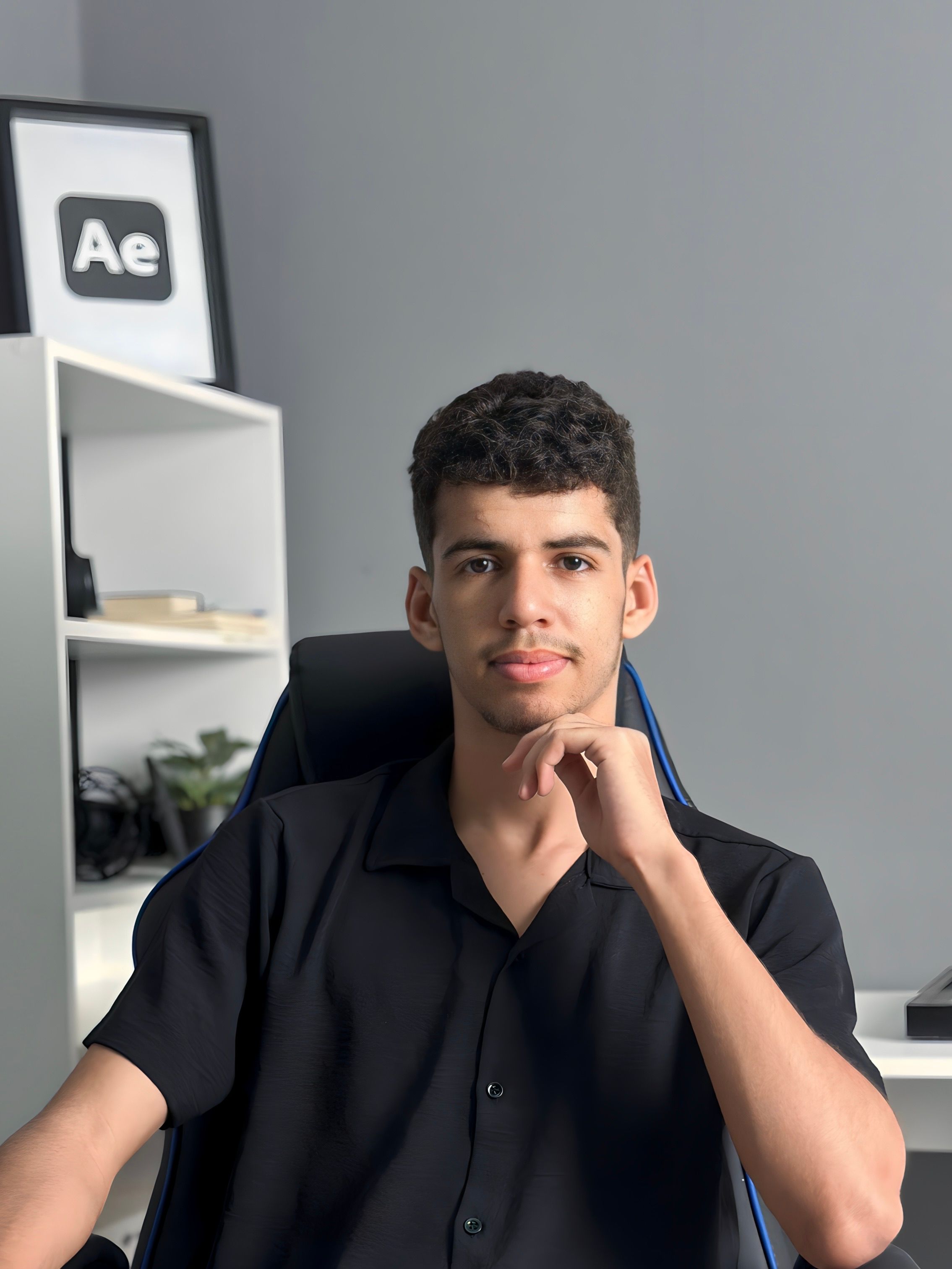 Young man in a modern workspace with tech-themed decor, posing confidently.