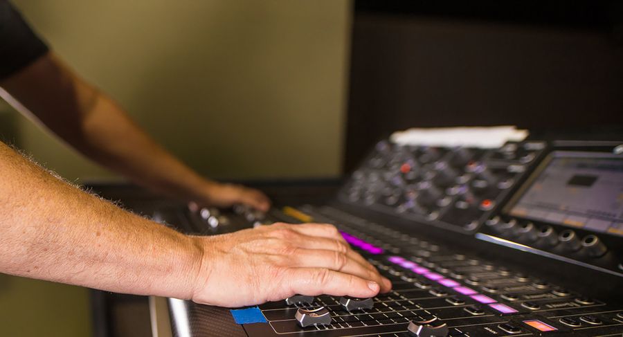 Mains de l'ingénieur du son sur la console de mixage