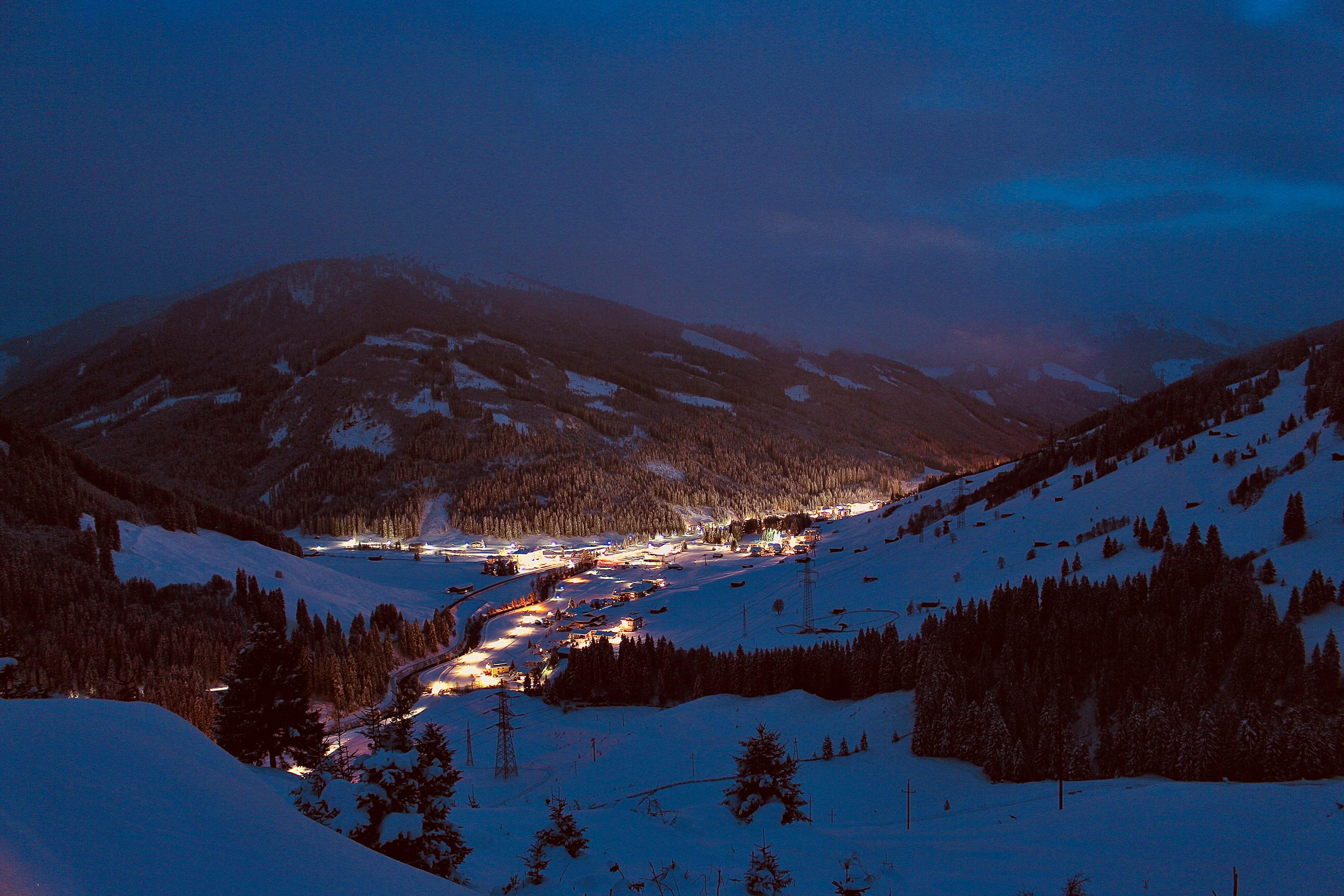 A breathtaking aerial winter night view of Gerlos, Tirol, Austria, with snow-covered mountains and illuminated village.