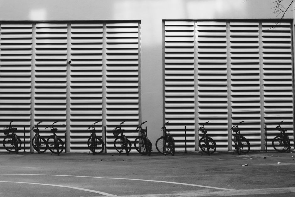 Row of bicycles against modern urban architecture in black and white.