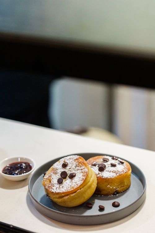 Free Delicious fluffy pancakes topped with chocolate chips and powdered sugar served with jam. Stock Photo