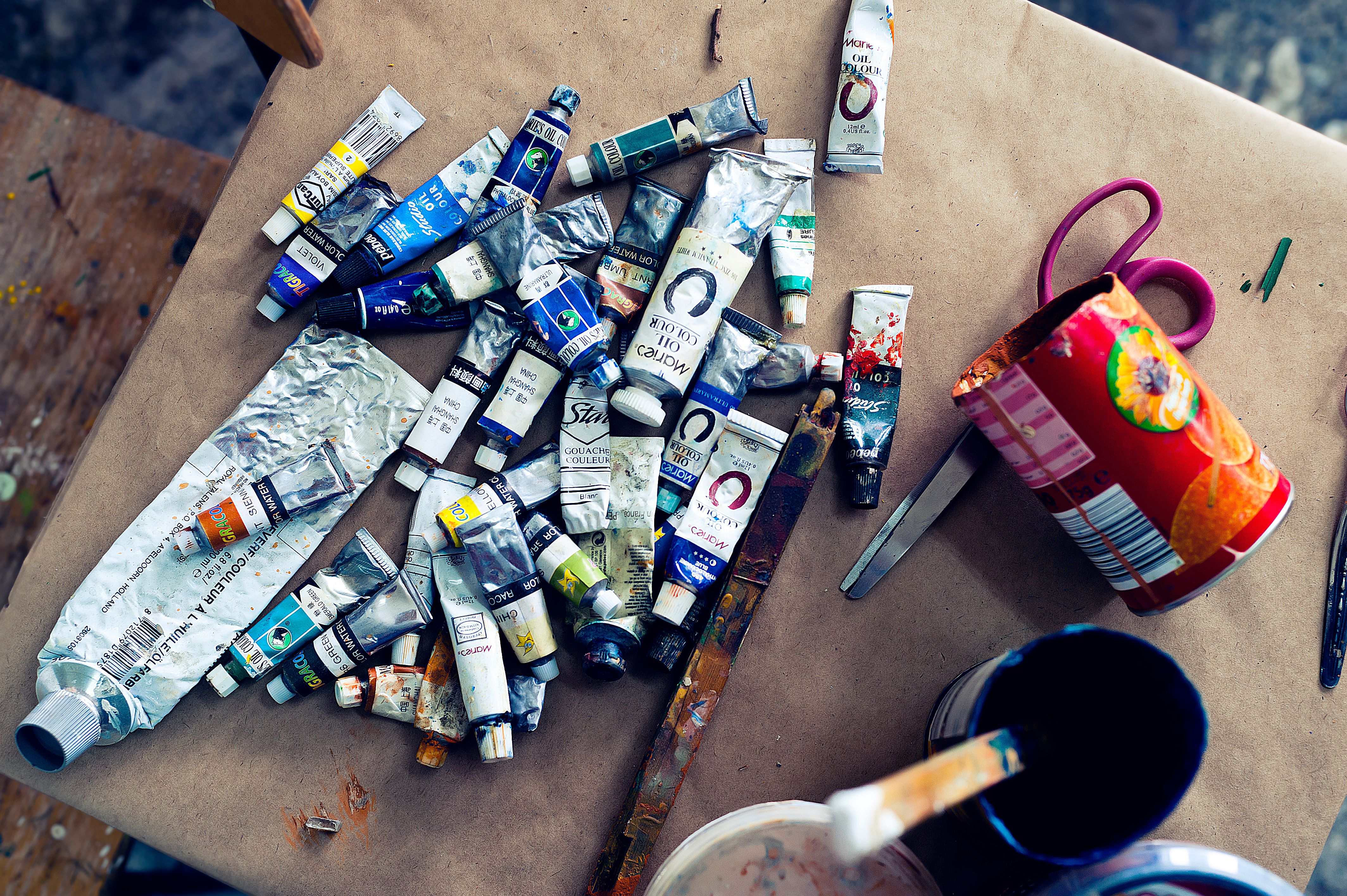 A variety of acrylic paint tubes scattered on a worktable in an art studio setting.