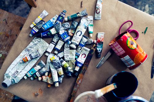 Free A variety of acrylic paint tubes scattered on a worktable in an art studio setting. Stock Photo