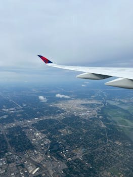 Aerial view of urban landscape and wing of an airplane on a cloudy day.