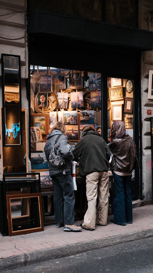Free Three adults browsing at an art gallery store window in a city street. Stock Photo