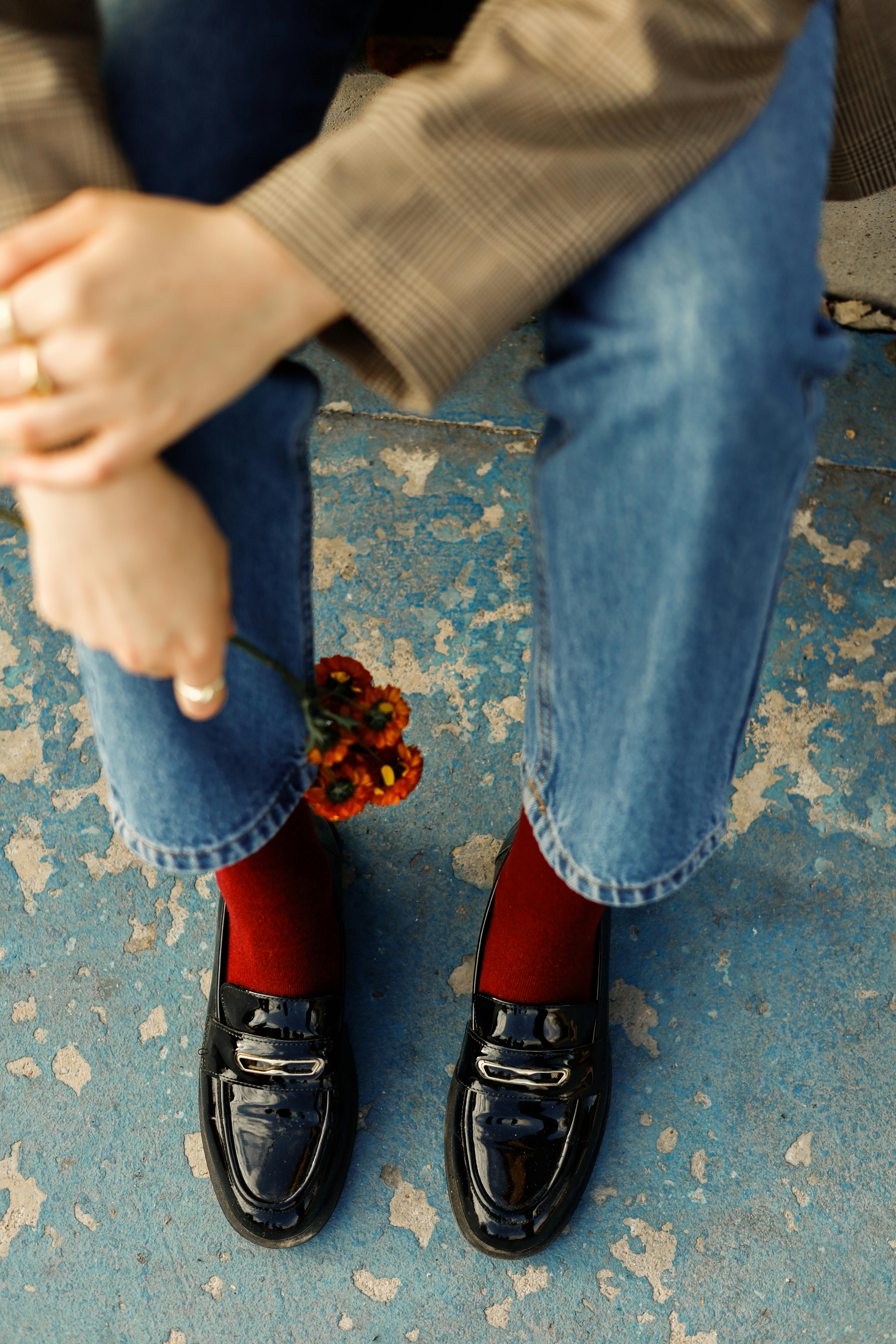 Chic outfit with shiny loafers, red socks, and denim jeans.