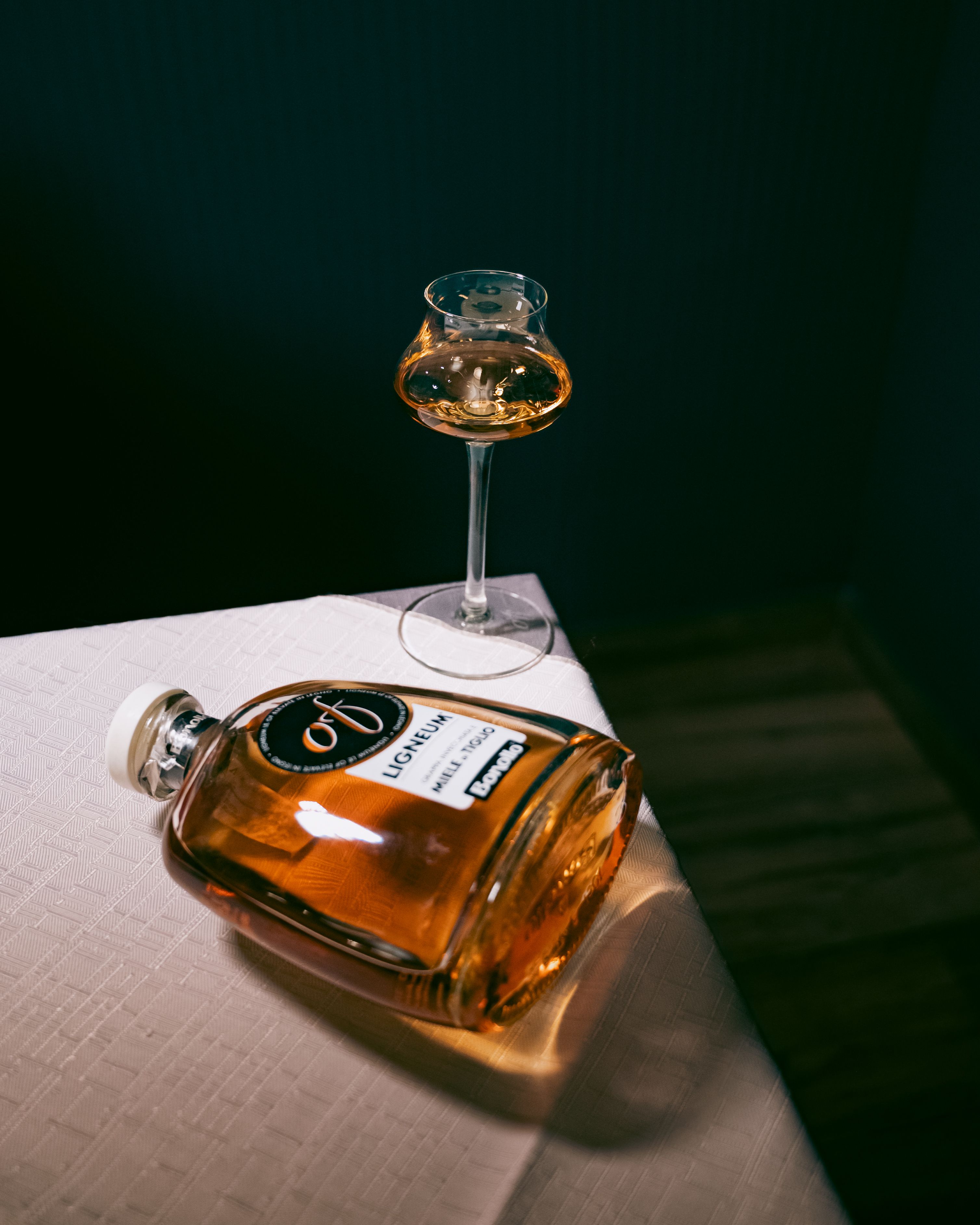 Elegant bottle of liqueur with a glass on a table in warm lighting, perfect for a refined drink theme.