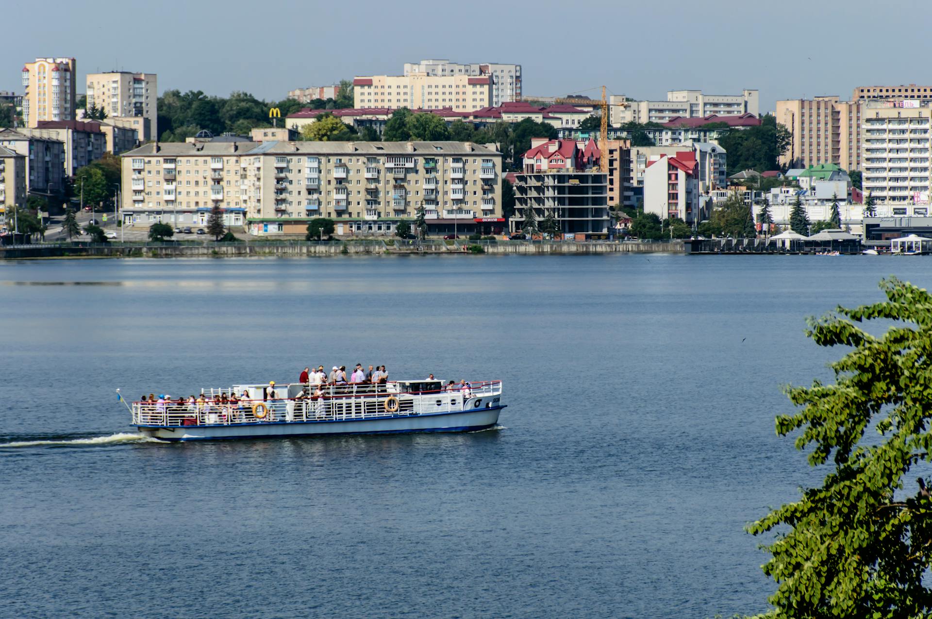 Passenger ship cruising on Ternopil Lake with urban skyline in the background.