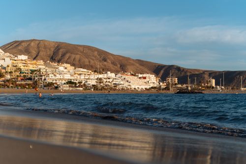 Free Capture of Los Cristianos beach with tranquil waters and sunset glow in the Canary Islands. Stock Photo