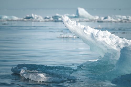 Free A stunning close-up of a glistening iceberg floating in the calm, cold waters of the Arctic ocean. Stock Photo