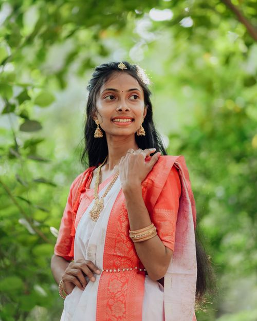 Free Portrait of a woman in vibrant Indian saree surrounded by lush greenery. Stock Photo