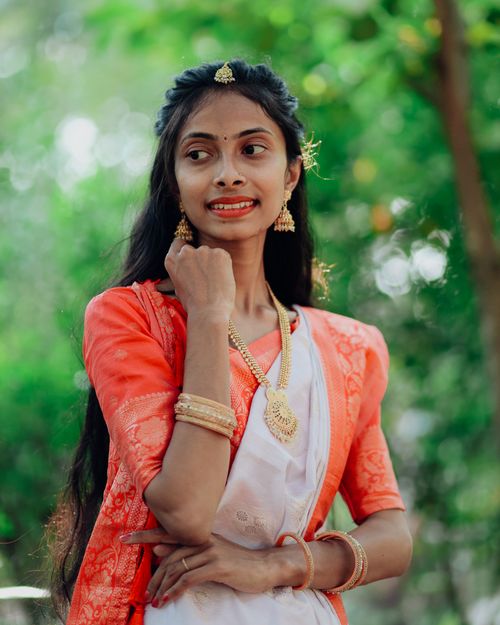 Free A woman in traditional Indian attire smiles outdoors surrounded by greenery. Stock Photo