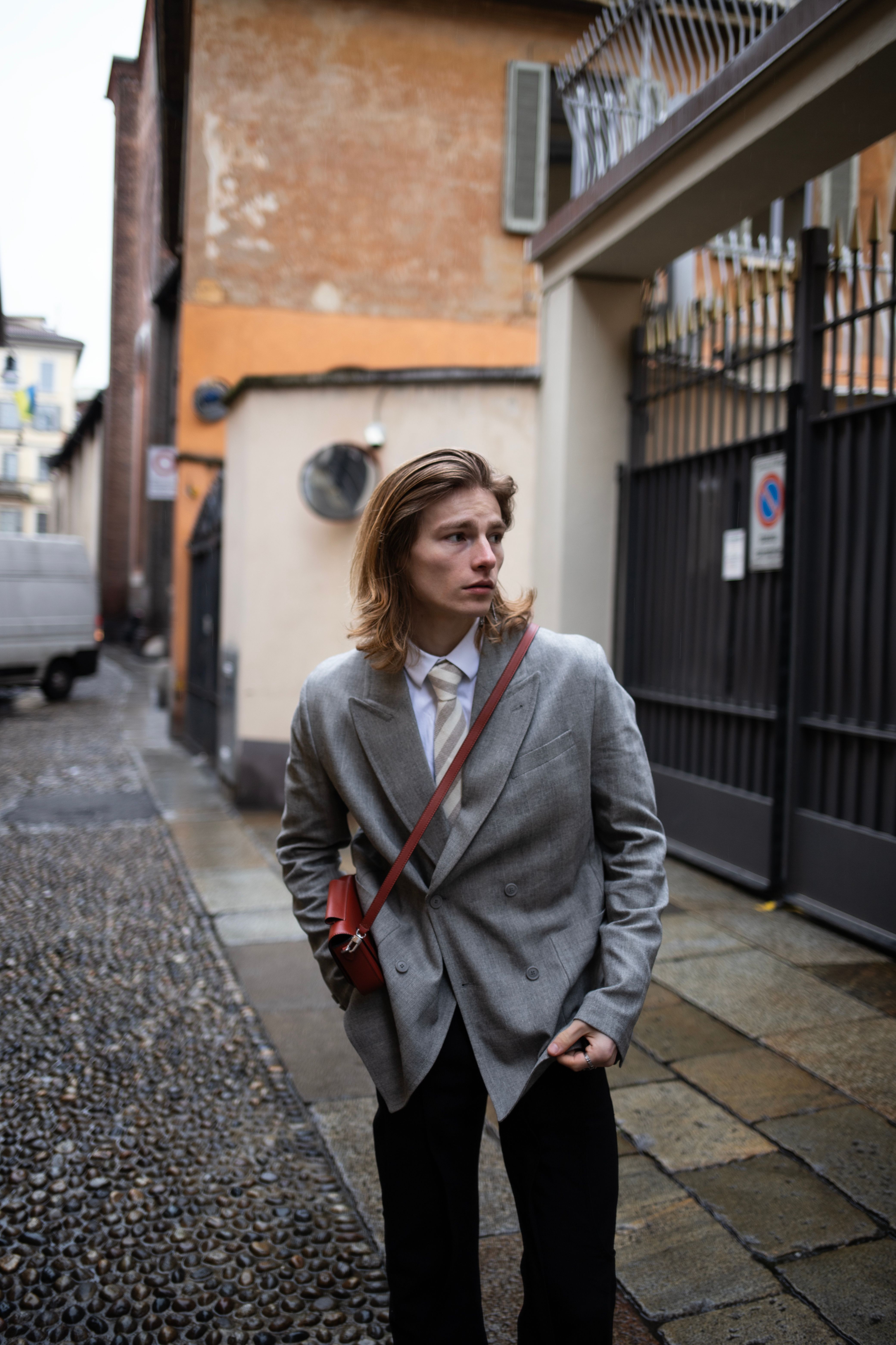 Fashionable young man in a coat walking in Milan street.