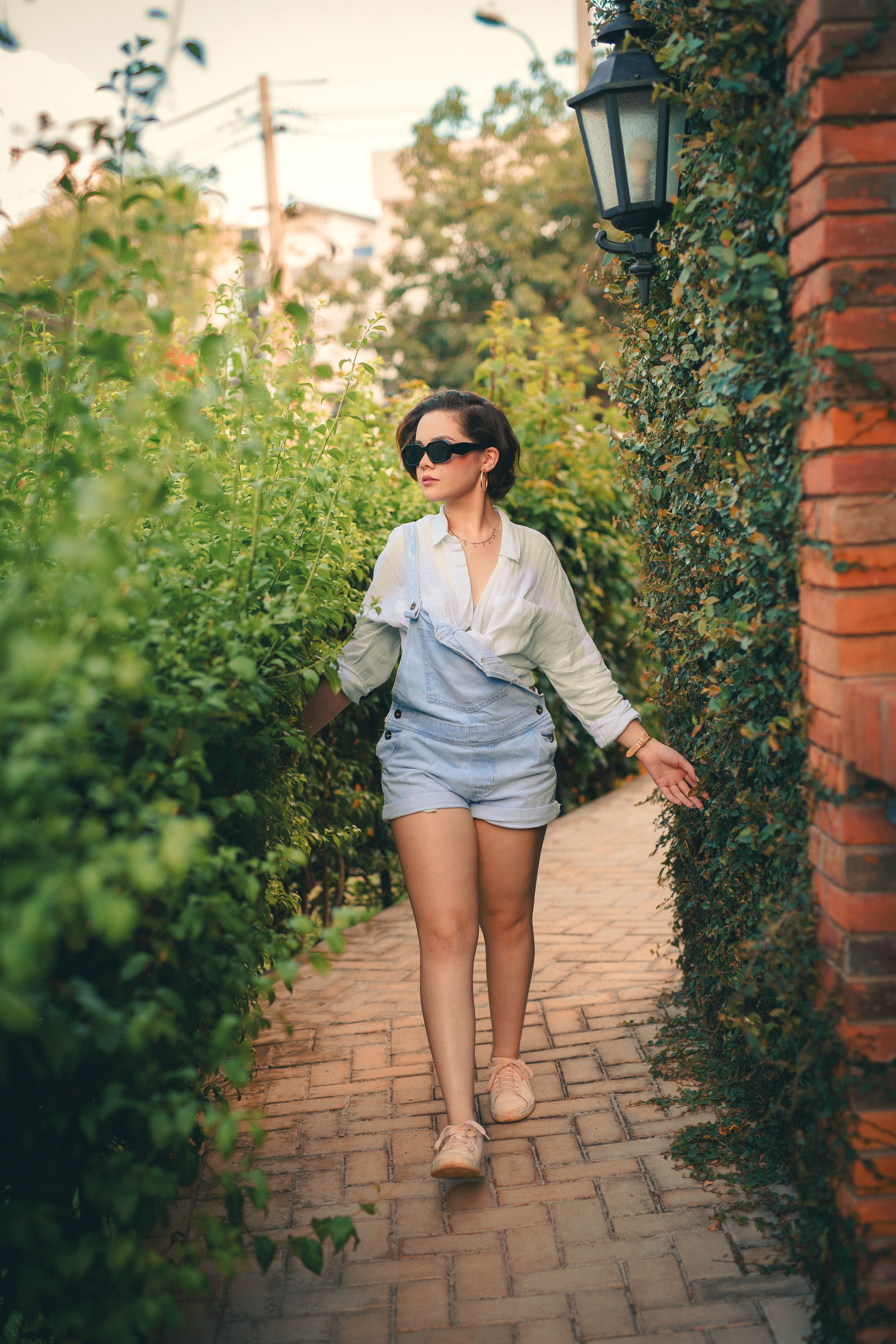 Woman Strolling Through Lush Garden Pathway · Free Stock Photo