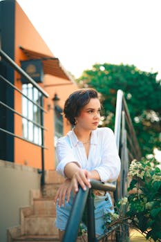 Young woman in casual summer attire leaning on a handrail outdoors.