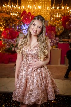 Teen girl in a sparkling dress enjoys an elegant celebration with festive decor.