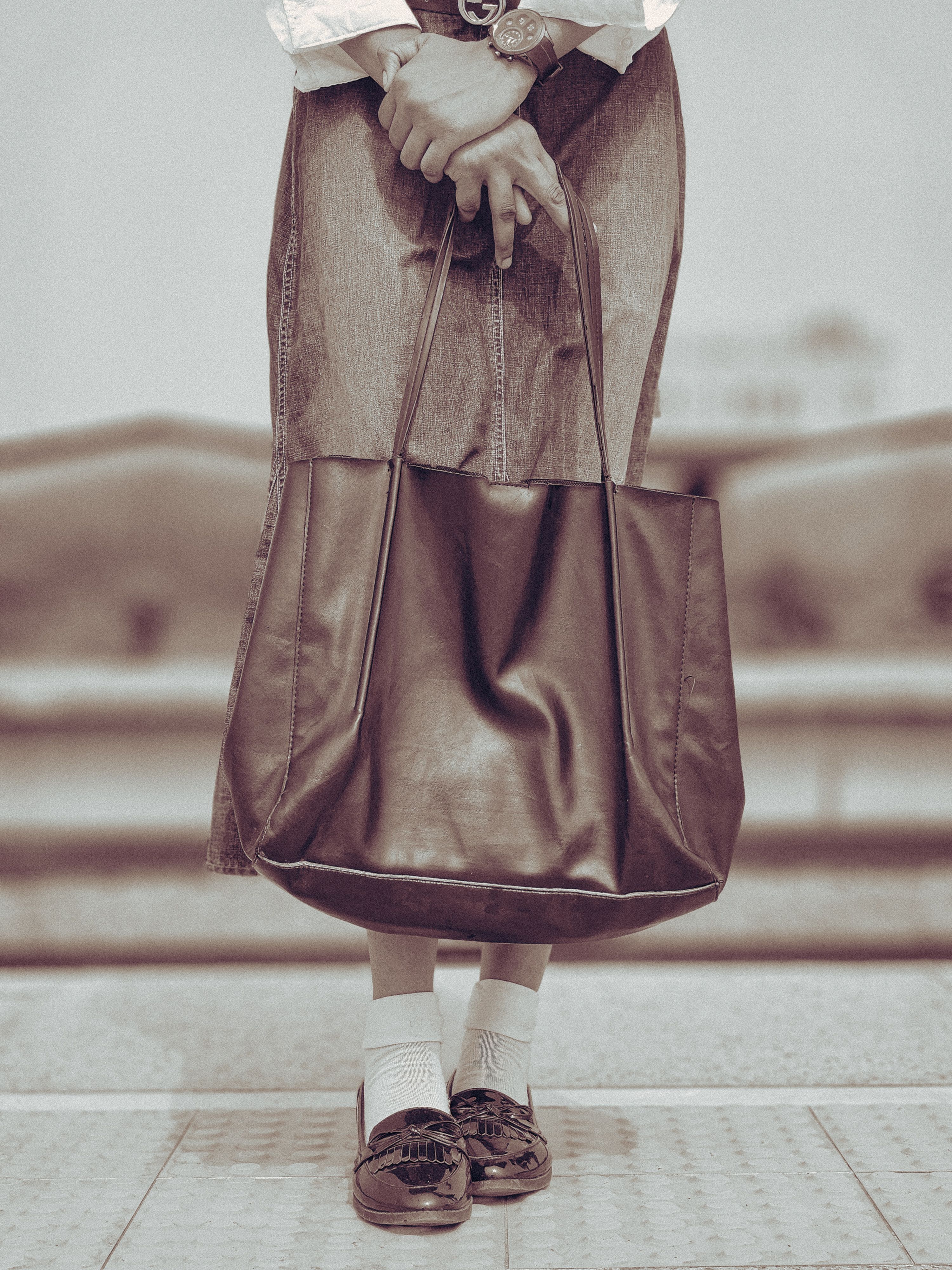 Bolsa tote de couro da moda combinada com saia jeans e mocassins, ideal para um estilo urbano chique.