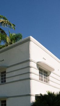 A stunning Art Deco building with palm trees under a clear blue sky.