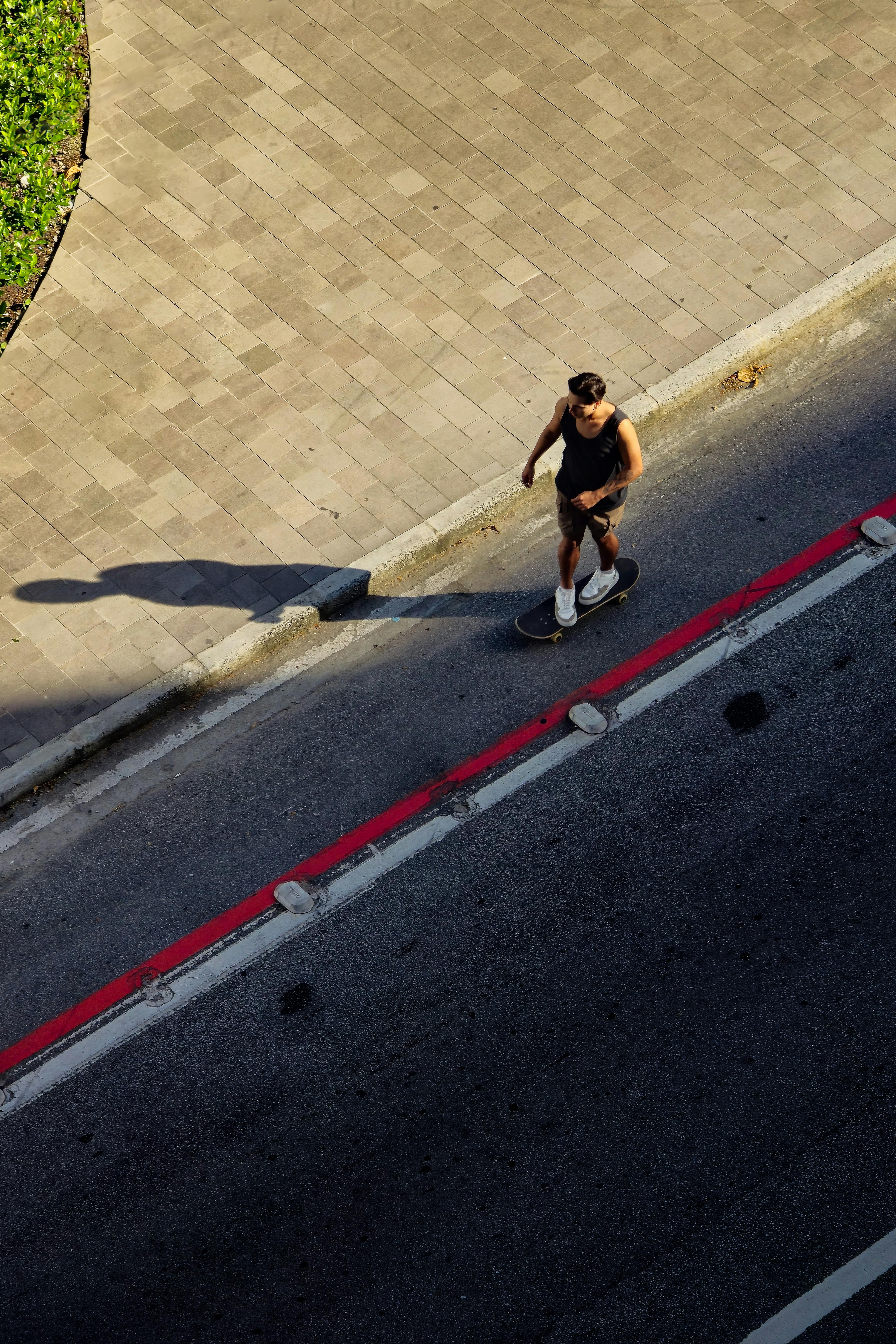 Skateboarder gliding along a sunlit city street, casting a long shadow.