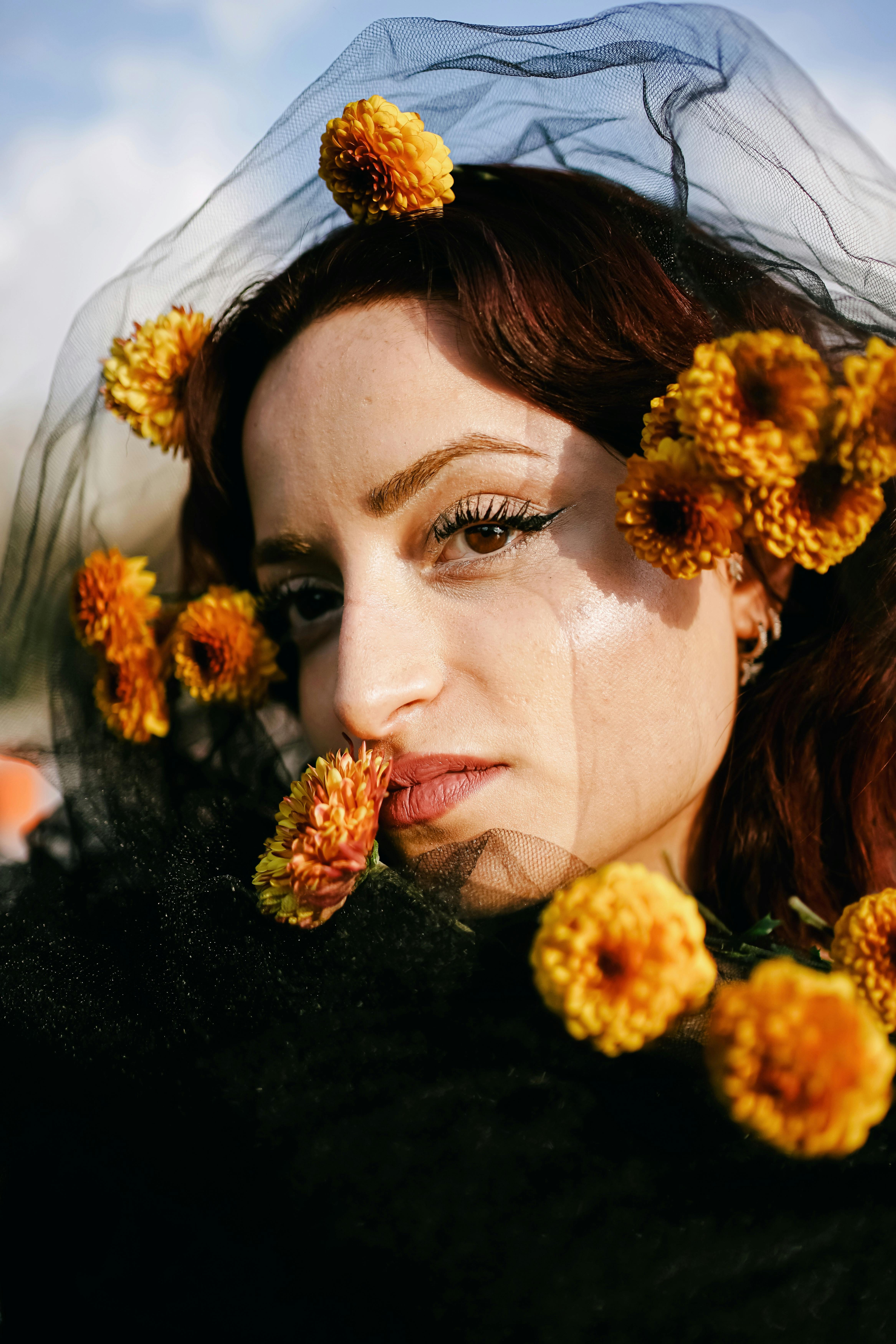 Artistic portrait of a woman with marigold flowers intricately placed in an outdoor setting.